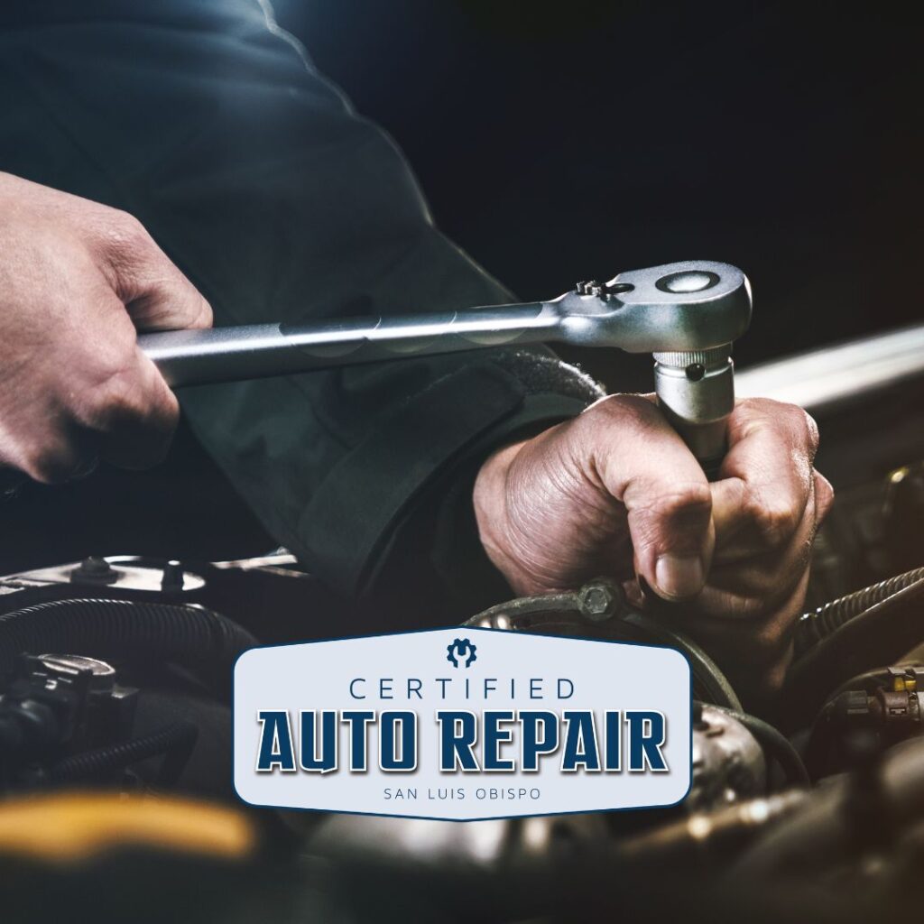 Close up on mechanic's hands using a wrench on a car engine.